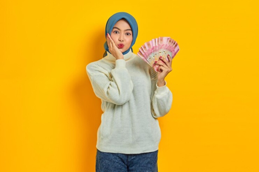 <p>Ilustrasi perempuan menunjukkan uang pecahan rupiah. Berikut cara cek penerima BSU dan jadwal pencairannya. (Foto: Freepik).</p>
