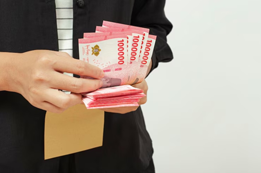 <p>Ilustrasi seseorang memegang uang rupiah. Berikut cara cek status penerima BSU 2025 di laman Kemnaker, BPJS Ketenagakerjaan, dan Pospay. (Foto: Freepik).</p>
