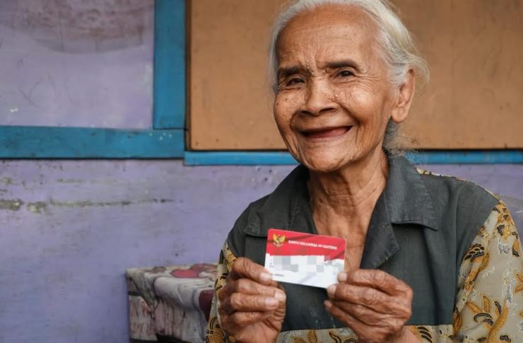 <p>Ilustrasi warga sedang memegang kartu untuk menerima bansos. Dana bansos PKH dan BPNT cair hingga 3,3 juta Langsung cek nama di situs resmi Kemensos. Foto : Kemensos</p>
