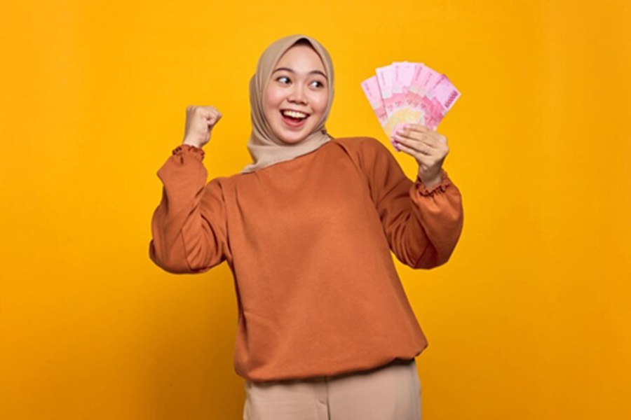 <p>Ilustrasi perempuan memegang uang rupiah. Berikut ini panduan lengkap cek status penerima BSU 2025 lewat HP di aplikasi JMO, mudah dan praktis. (Foto: Freepik).</p>
